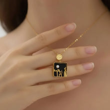 Gold necklace with a pendant featuring a design of two people holding hands against a black background, worn by a person.