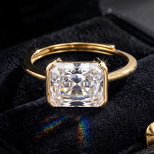 A gold-plated adjustable ring featuring a large, clear rectangular princess-cut gemstone, displayed on a black velvet jewelry box. The brand logo 'Orisa Jewels' is visible in the top-left corner.