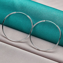 Silver hoop earrings on a teal and gray fabric background with 'Doteffil' branding.