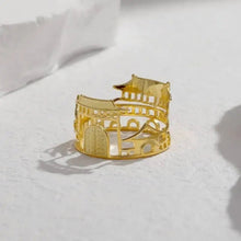 Gold bracelet with architectural design on a white surface, featuring the brand 'Geezenca'.
