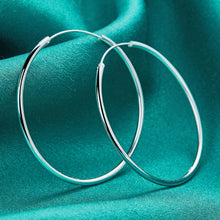 Silver hoop earrings on a teal fabric background with 'Doteffil' branding.