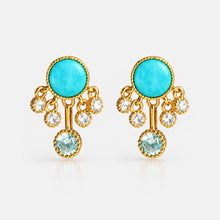 Pair of earrings with turquoise stones and gold accents on a white background, featuring the brand 'Geezenca'.