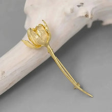 Gold flower-shaped earring on a gray background.