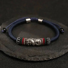 Navy blue bracelet with silver and multicolored beads on a dark stone surface